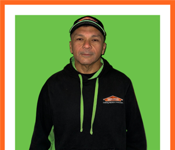 SERVPRO employee in front of green wall